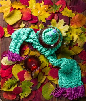 Blurred autumn leaves background with hot steaming cup of tea