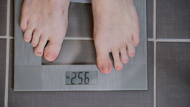 Male feet on glass scales, men's diet, body weight, close up, man standing on scales, top down view, athlete foot