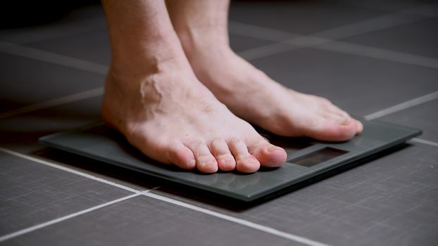 Male feet on glass scales, men's diet, body weight, close up