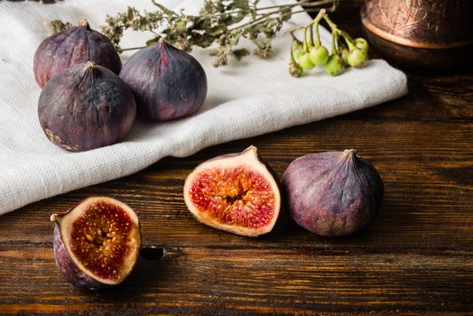 Ripe seasonal figs on the cloth and wooden surface with sliced one