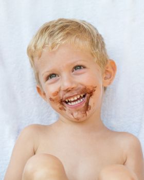 Portrait of fair-haired boy with chocolate on his face isolated on white background,baby boy smile.