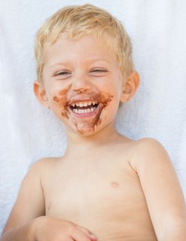Portrait of fair-haired boy with chocolate on his face isolated on white background,baby boy smile.