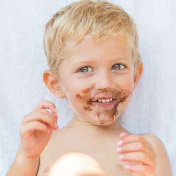 Portrait of fair-haired boy with chocolate on his face isolated on white background,baby boy smile