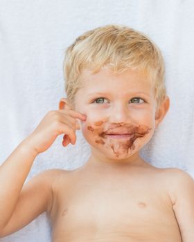 Portrait of fair-haired boy with chocolate on his face isolated on white background,baby boy smile