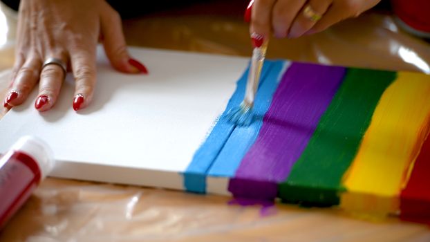 Female artist painting a rainbow with acrylic colors on canvas, hoe made art, DIY tutorial, colorful