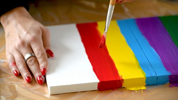 Female artist painting a rainbow with acrylic colors on canvas, hoe made art, DIY tutorial, colorful