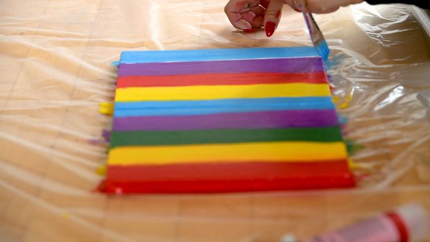 Female artist painting a rainbow with acrylic colors on canvas, hoe made art, DIY tutorial, colorful