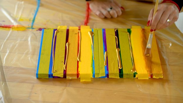 Female artist painting a rainbow with acrylic colors on canvas, hoe made art, DIY tutorial, colorful, painting with gold, tape mask for pattern