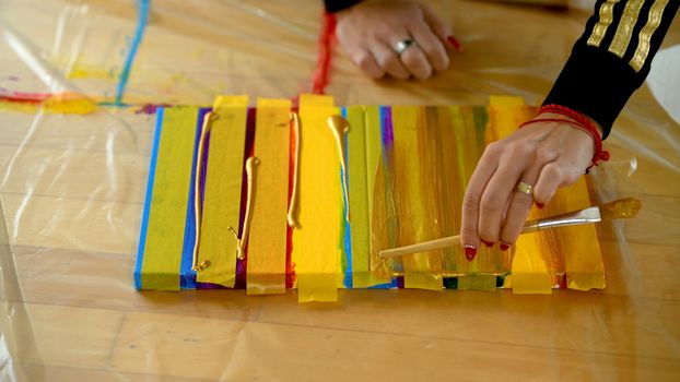 Female artist painting a rainbow with acrylic colors on canvas, hoe made art, DIY tutorial, colorful, painting with gold, tape mask for pattern