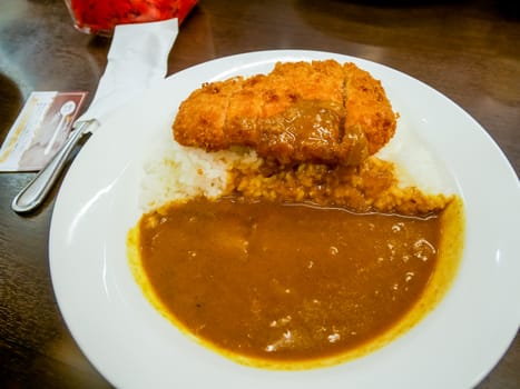 Spicy crispy pork cutlet omelet curry serve on white dish.