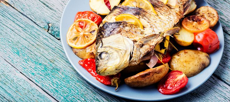 Grilled fish with potato and lemon on wooden background