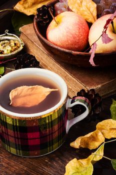 Teacup on an autumn background of fallen leaves and apples .Autumn postcard