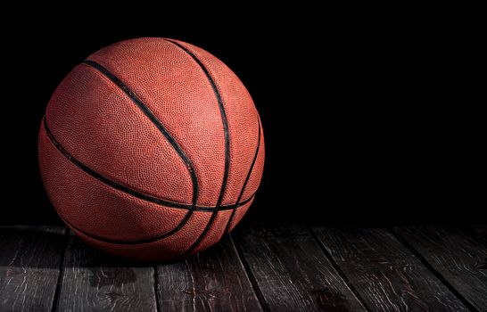 Basketball ball on a wooden floor. Black background.