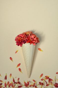 Autumn flowers in ice cream cone on paper background