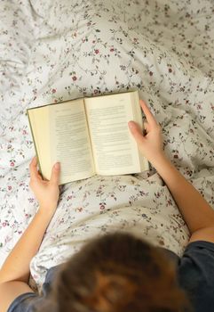 Girl reading a book in bed