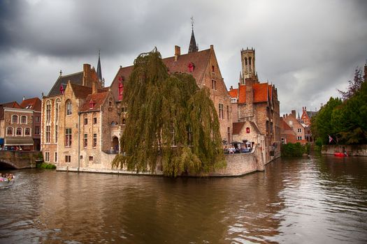 BRUGES, BELGIUM - SEPTEMBER 05, 2018: Canal in Bruges and famous Belfry tower on the background in a beautiful autumn day, Belgium on September 05, 2018