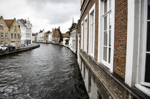 BRUGES, BELGIUM - SEPTEMBER 05, 2018: Canal in Bruges and famous Belfry tower on the background in a beautiful autumn day, Belgium on September 05, 2018