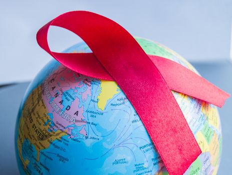 World AIDS day 1 December, close-up of world globe with red ribbon.