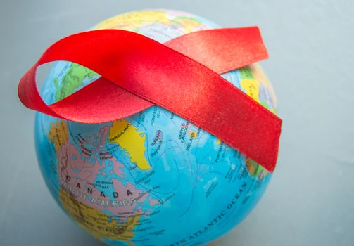 World AIDS day 1 December, close-up of world globe with red ribbon.