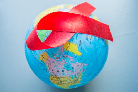 World AIDS day 1 December, close-up of world globe with red ribbon.