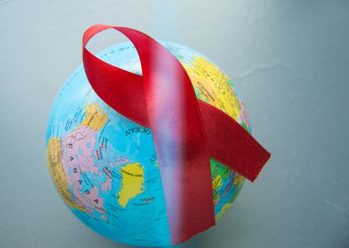 World AIDS day 1 December, close-up of world globe with red ribbon.