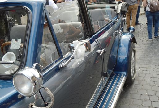 Vintage luxury car convertible decorated with white wedding bow.