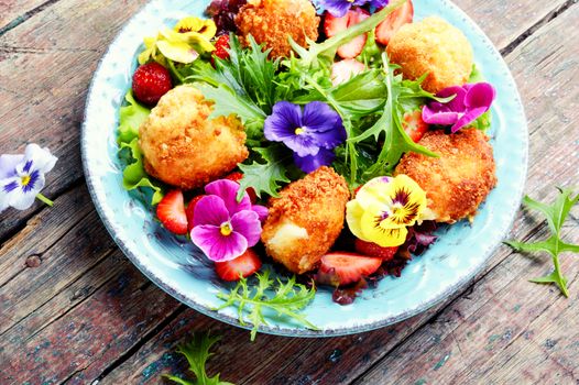 Vitamin summer salad with strawberries, grilled cheese, arugula and flowers.Healthy food