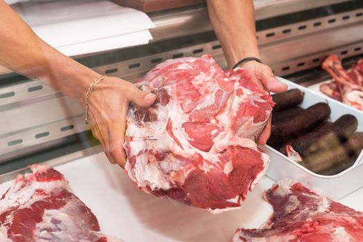 Butcher offering fresh meat at display in butchery