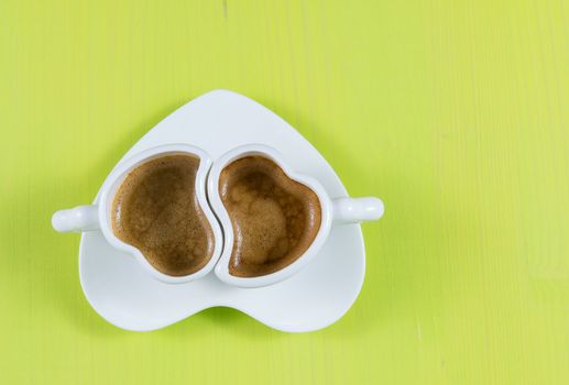 Flat lay with two cups of espresso coffee on a green wooden board. Concept for romance