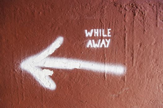 Arrow on a wall with text, detail of an indication, while away