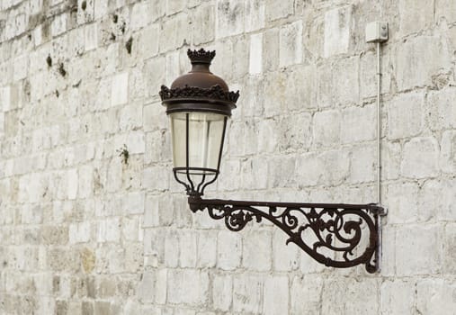 Old street lamp on a wall, detail of city lighting, electricity and light