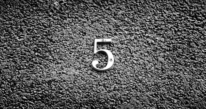 Number five on the wall of a house, detail of a number of information, odd number