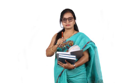 An Indian teacher with a book and pen giving explanation, on white studio background.