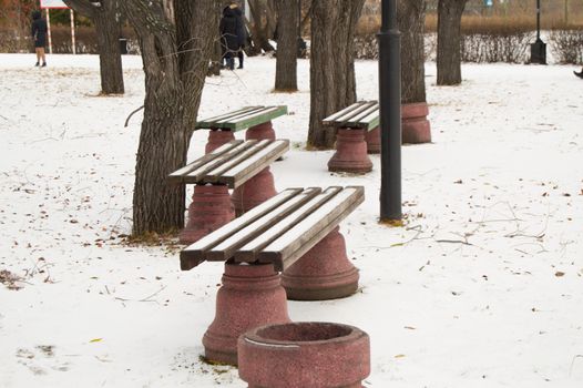 Several wooden benches in the winter city Park, the first snow.