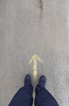Feet in front of an arrow, detail of a direction arrow, sign