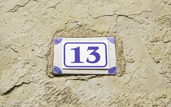 Number thirteen on a wall, detail of a number of information, odd number, superstition