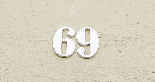 Number sixty nine on the wall of a house, detail of a number of information, odd number