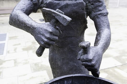 Bronze statue with a hammer, detail of a statue of a worker