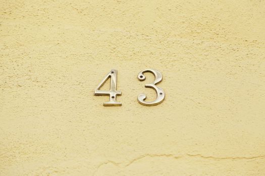 Number forty-three on the wall of a house, detail of a number of information, even number