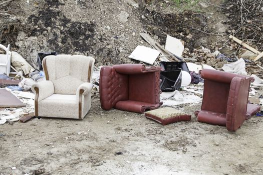 Sofas broken and abandoned, detail of furnishings from left, dirt and debris