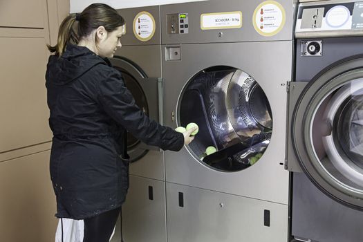 Young woman in a laundry, detail of person washing clothes, cleaning and hygiene