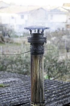 Old chimney with smoke, detail of a tube to expel smoke heating