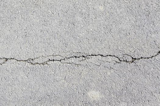 Cracked asphalt, detail of a broken and cracked road