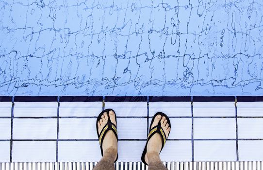 Man's feet in the water of a pool, detail of summer and refreshment, heat