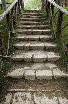 Old stairs in a green forest, detail of access to the dark forest