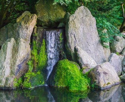 beautiful waterfall with streaming water with big stones and some covered with green moss peaceful nature scenery background