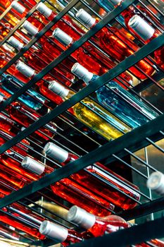 Rows of colourful wine bottles, Detail image of Metal rack with plenty of wine bottles composed in rows for decor.