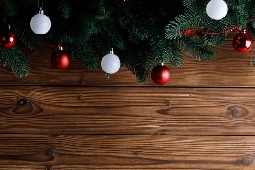 Christmas tree decoration frame on wooden background , fir tree branch , red and white baubles , copy space for text