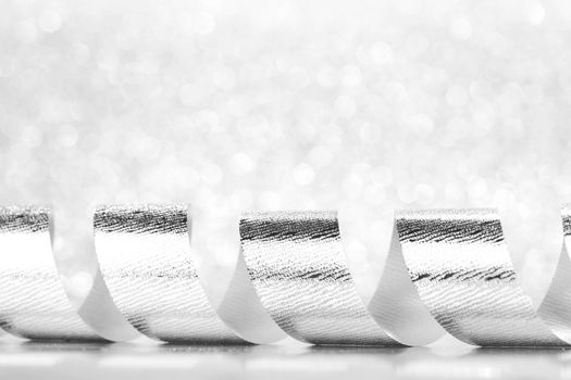Shiny silver gift ribbon on bokeh background close-up