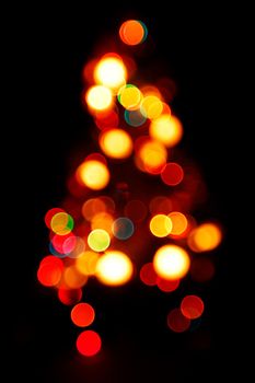 Bokeh silhouette of Christmas tree on black background